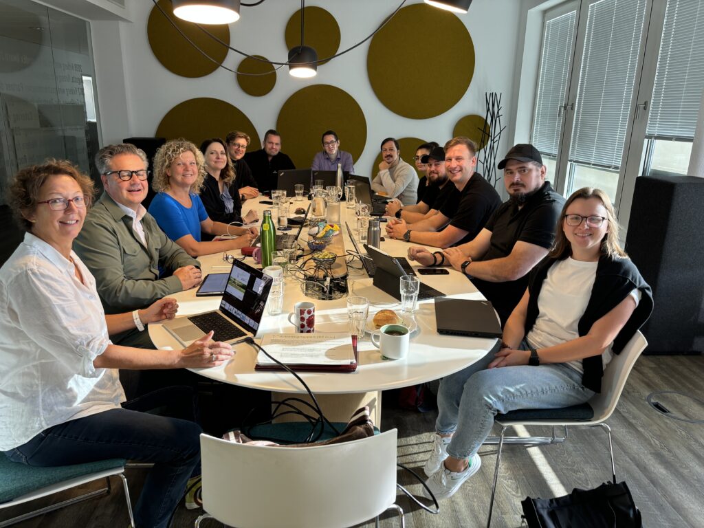 Bild von 11 Kirberg Catering Mitarbeitern, die bei einem Gemeinwohl-Ökonomie-Workshop um einen Konferenztisch herum sitzen.