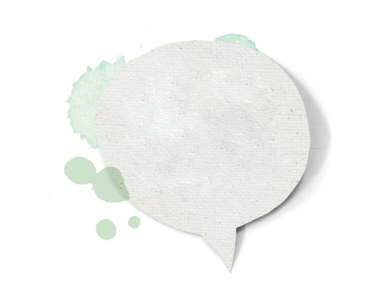 Eine leere Sprechblase aus Papier mit grünen Aquarellspritzern auf weißem Hintergrund.