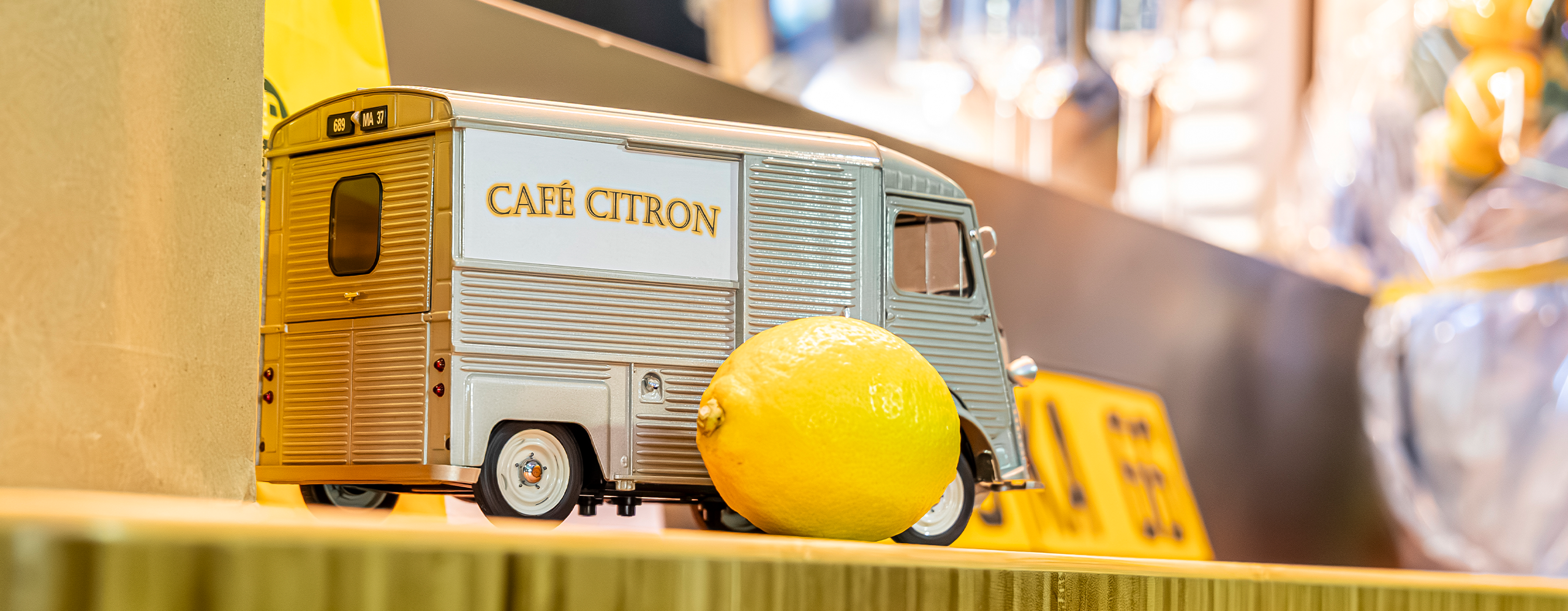 Miniaturmodell des Café-Citron-Citroën-HY mit Zitrone als dekoratives Element auf der Cateringtheke.